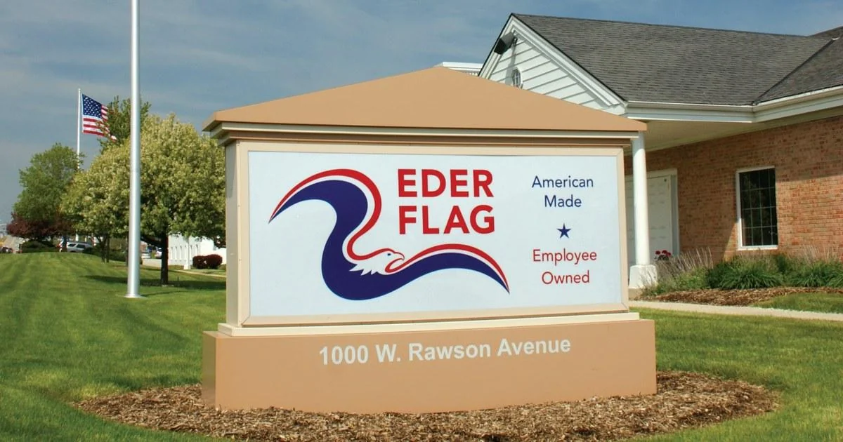 Eder Flag company sign outside its facility at 1000 W. Rawson Avenue, with an American flag in the background.